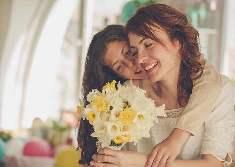 Tochter schenkt Mutter einen Blumenstrauss mit gelben Blüten