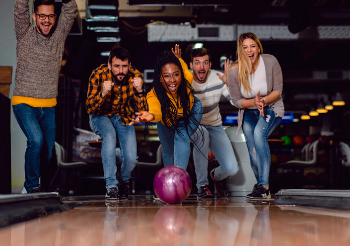 Eine Gruppe von Freunden hat bei der Indoor Aktivität Bowling eine gute Zeit und lacht