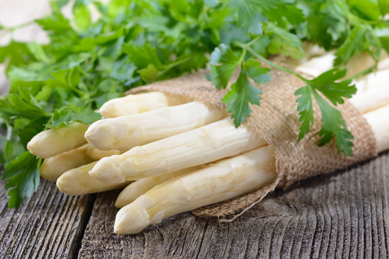 Weißer Spargel liegt mit Petersilie auf dem Tisch