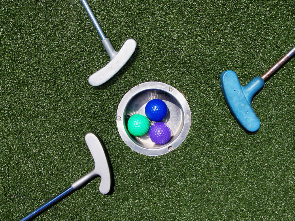 Minigolfschläger mit Bällen im Loch