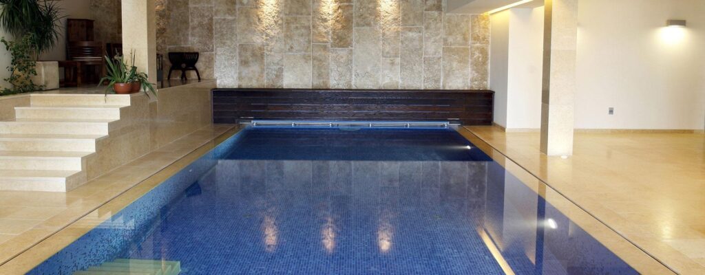 privates Indoor-Schwimmbecken mit dunkelblauen Fliesen und heller Eingangstreppe